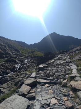 path leading up towards mountain, with the sun very bright in the background