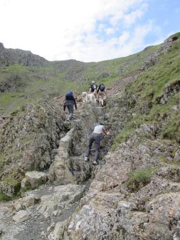 group of people clambering up a rocky path
