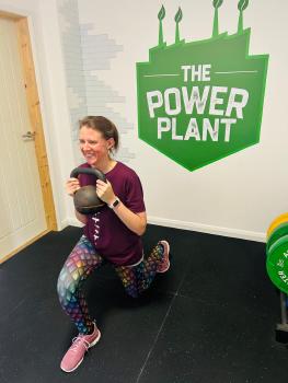 Emilie doing a lunge holding a kettlebell.