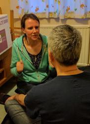 Image of a dark-haired woman, sitting looking at another person, as if they are talking together