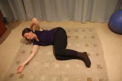 Image of dark-haired woman in purple top and black leggings, lying on her side with one hand behind her head