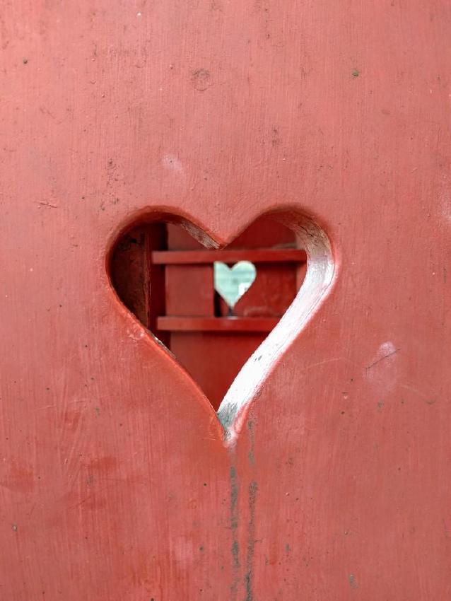 Image of a heart-shaped hole carved into red-painted wood