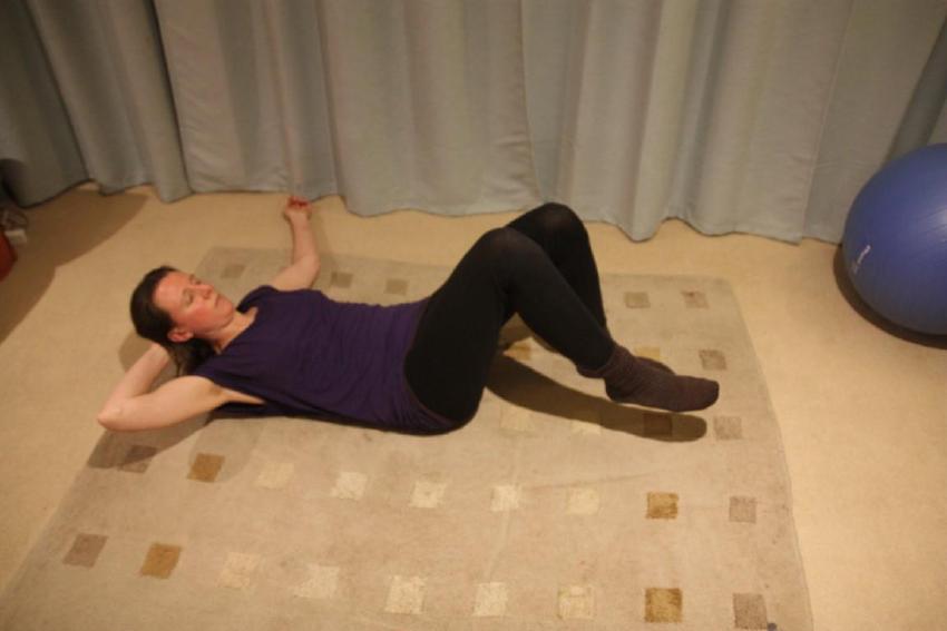 Image of person lying on back lifting head and leg