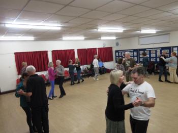 Image of people dancing in couples in a circle with the teacher in the centre